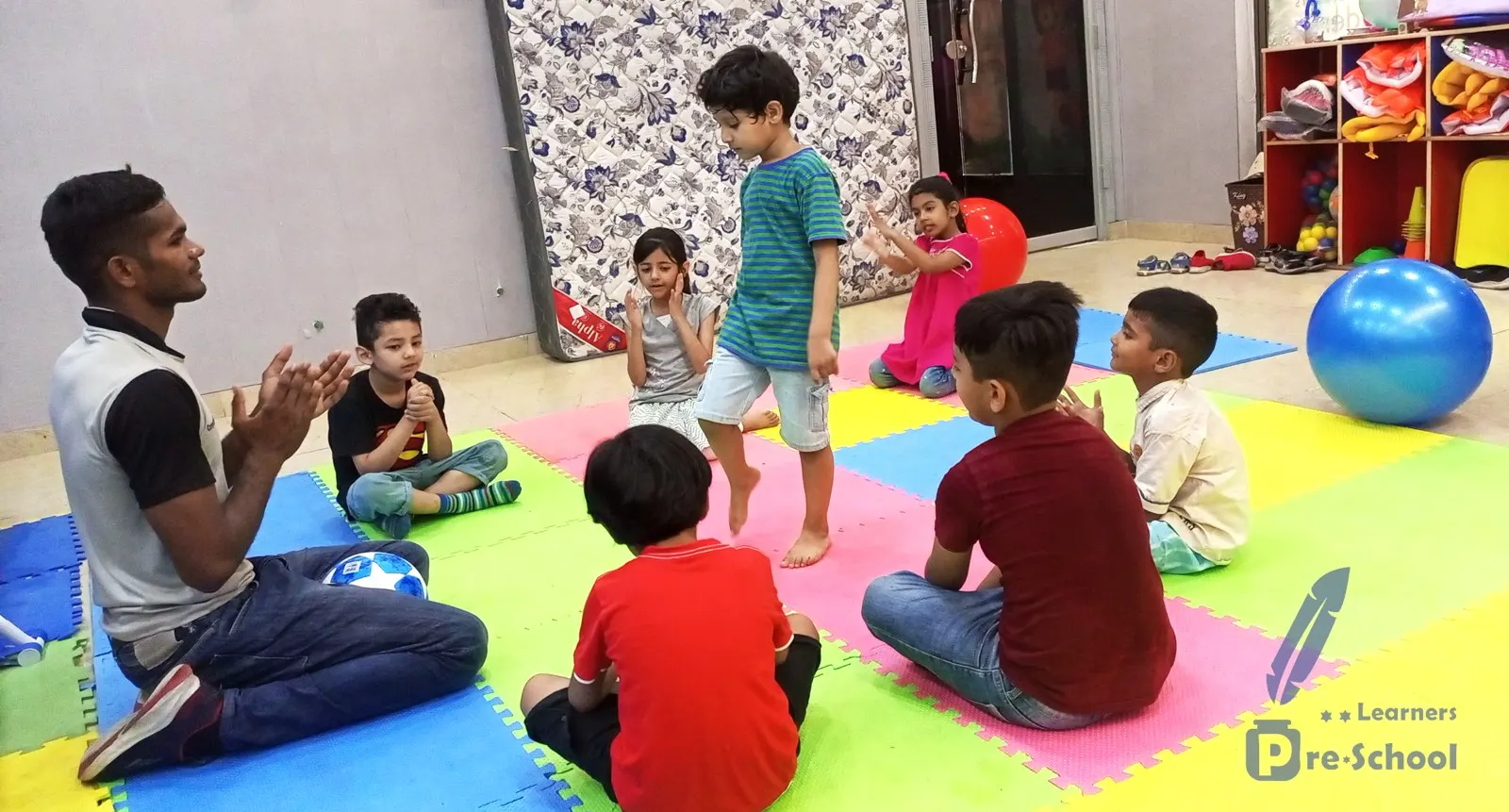 A group activity on the classroom floor mats with a teacher