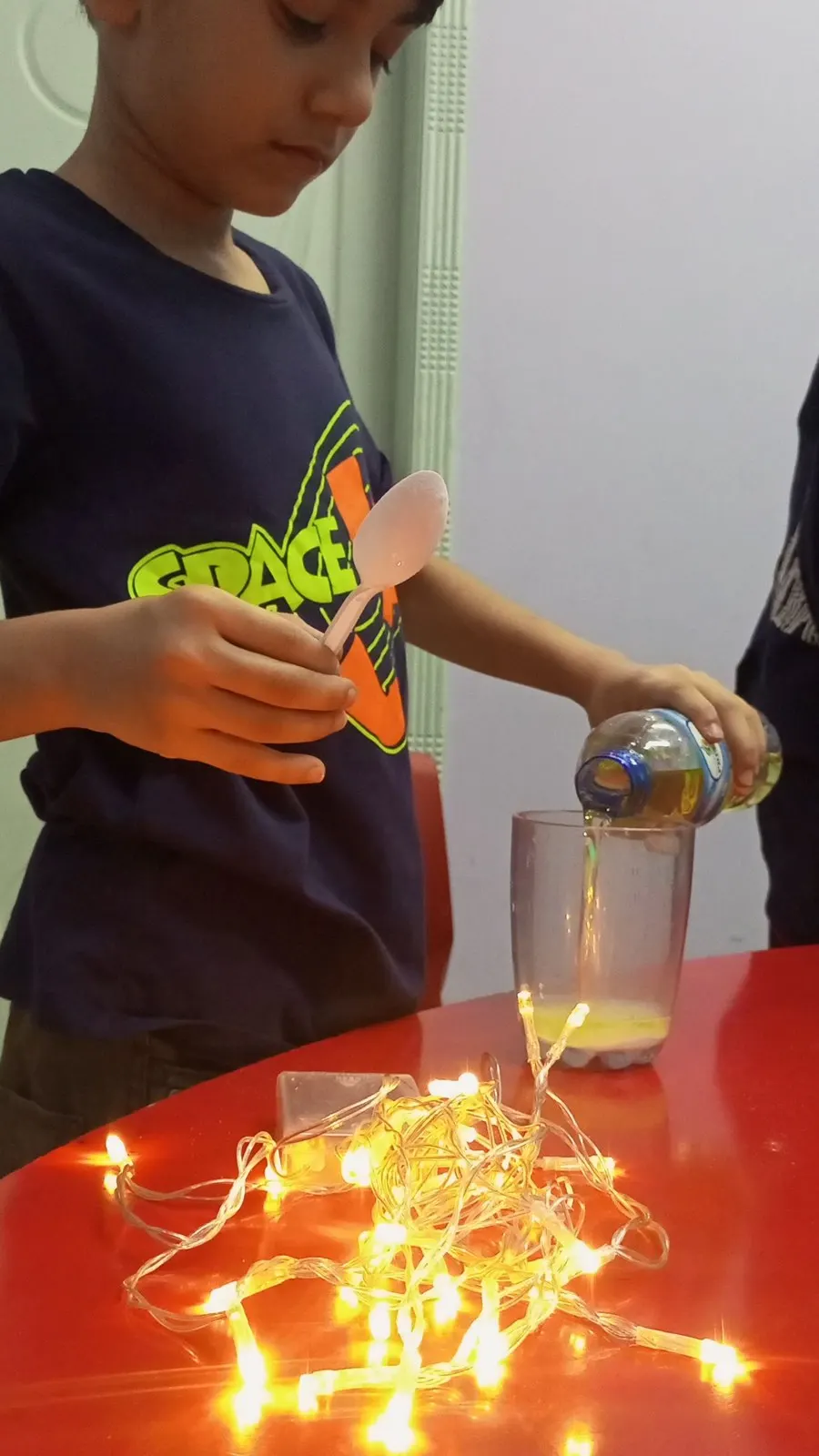 A student pouring liquid into a jar during a lava-lamp science experiment