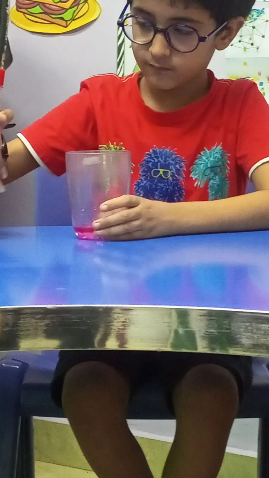 A student watching colours mix in a glass during a science experiment